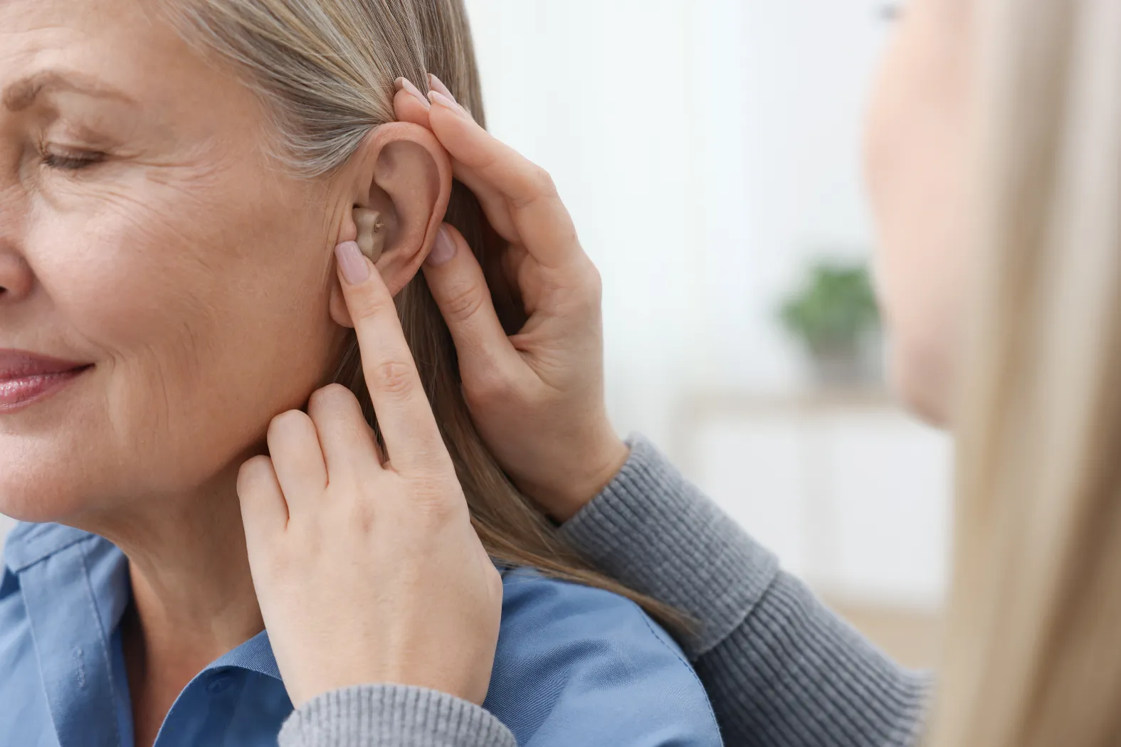 Audiologist professionally fitting a hearing aid for a patient