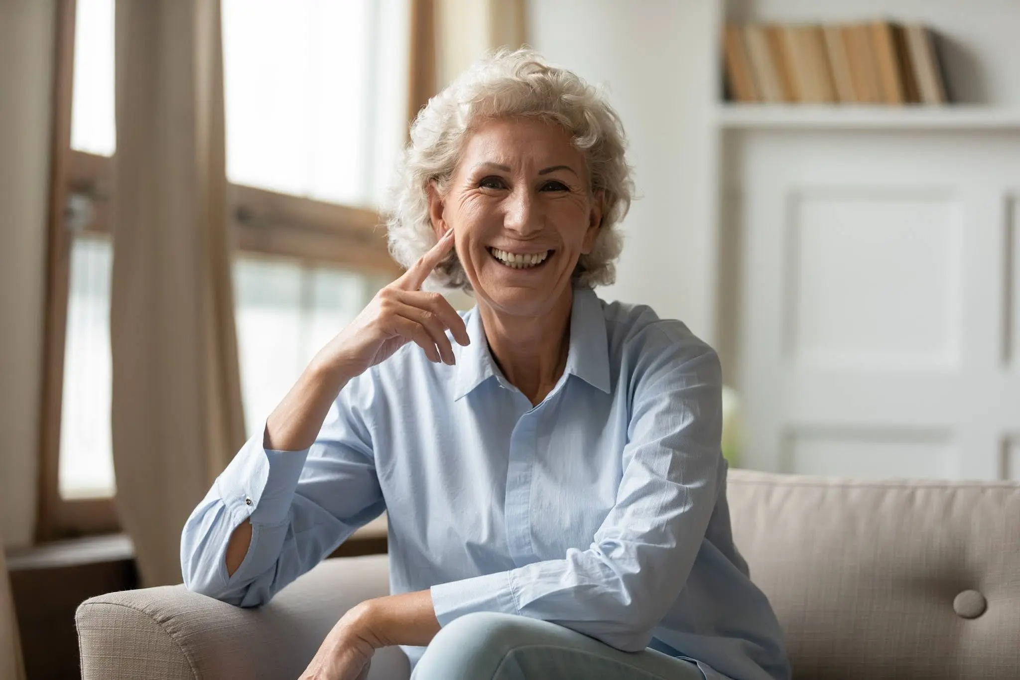 Elderly woman sitting on sofa, smiling